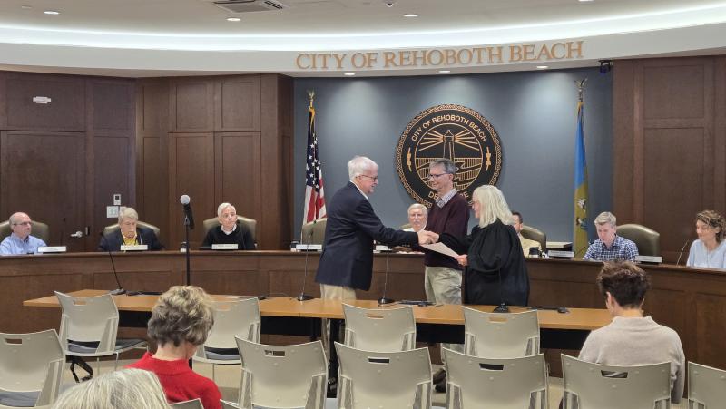 Rehoboth Beach commissioners voted in favor of Mark Saunders filling the seat of former Commissioner Don Preston, who stepped down a few weeks ago with nearly two years left on his term. Shown, with husband Bob Thoman in the middle, is Saunders shaking the hand of Alderman Court 37 Judge Renee L. Bennett after being sworn in. CHRIS FLOOD PHOTOS